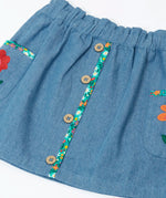 Close up of the buttons on the front of the Frugi Selena child's denim skirt with wildflower trims and wildflower embroidery on the side pockets.