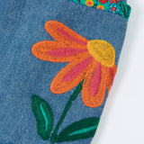 Close up of an embroidered flower on the side pockets of the Frugi Selena child's denim skirt with wildflower trims.