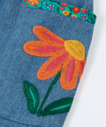 Close up of an embroidered flower on the side pockets of the Frugi Selena child's denim skirt with wildflower trims.
