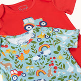 Close up of the front of the A two pack of Frugi short sleeve baby vests laid out on top of each other. One with a plain red background and a blue tractor printed on the front the other had a on the farm themed all over print featuring farm animals, tractors, leaves and plants on a light blue background.
