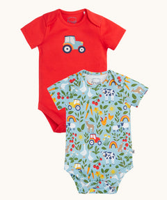 A two pack of Frugi short sleeve baby vests. One with a plain red background and a blue tractor printed on the front the other had a on the farm themed all over print featuring farm animals, tractors, leaves and plants on a light blue background.