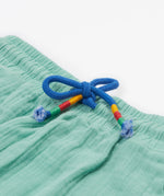 A close up of Frugi Mateo Shorts in the colour Moss, featuring a blue drawstring.