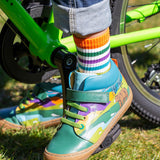 A close up of the Frugi Sky Stretch children's leather Lace Boot with a holly green bear design being worn by a child. The child is riding a bike.