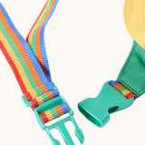 A close up of the green coloured quick release buckle closure on the rainbow coloured strap of the Frugi smiley face children's belt bag. 