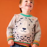 Child wearing the Frugi snow leopard organic cotton character knit jumper with 3d ears, green neck trim and rainbow arm cuffs and hemline. 