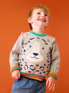 Child wearing the Frugi snow leopard organic cotton character knit jumper with 3d ears, green neck trim and rainbow arm cuffs and hemline. 