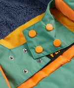 A close up of the Frugi kids snow and ski coat in green with a mountain scene print. Showing the thick navy fleece on the back and popper fasteners to adjust the size for a snug fit
