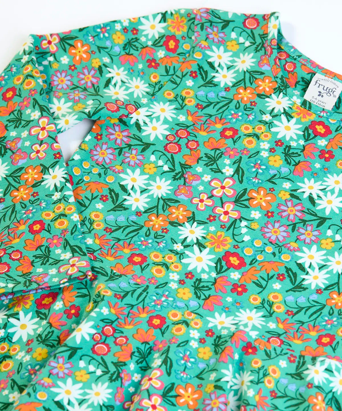 Close up of the front of the Frugi Sofia organic cotton kids long sleeved skater dress in green with an all over wildflower wander print. 