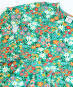 Close up of the front of the Frugi Sofia organic cotton kids long sleeved skater dress in green with an all over wildflower wander print. 