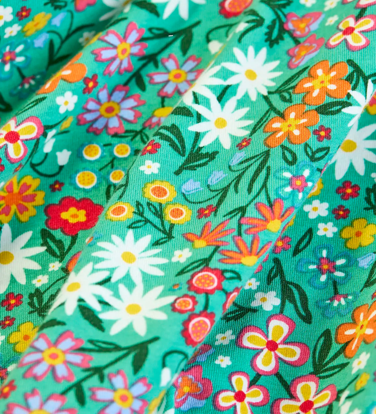 Close up of the print on the Frugi Sofia organic cotton kids long sleeved skater dress in green with an all over wildflower wander print. 