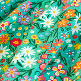 Close up of the print on the Frugi Sofia organic cotton kids long sleeved skater dress in green with an all over wildflower wander print. 