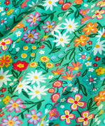 Close up of the print on the Frugi Sofia organic cotton kids long sleeved skater dress in green with an all over wildflower wander print. 