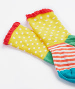A close up of the Frugi kids Freya sock. Showing the yellow spotted sock with a striped design and light pink frill on organic cotton fabric