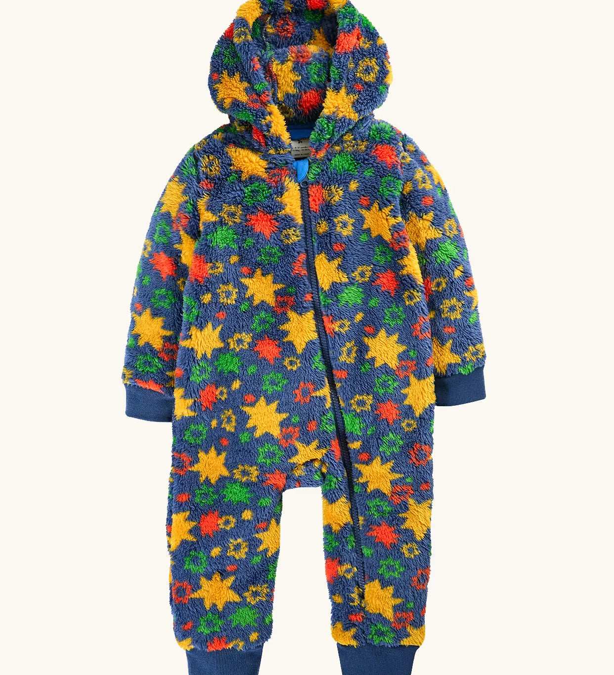 A frugi hooded one-piece baby jumpsuit in a fuzzy fleece material, featuring a vibrant multicolor star pattern on a navy blue base. The jumpsuit has a front zipper, ribbed cuffs, and ribbed ankle cuffs.