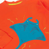 A close up of the front of the Frugi orange children's jumper with a large blue coloured ray applique on the front. 