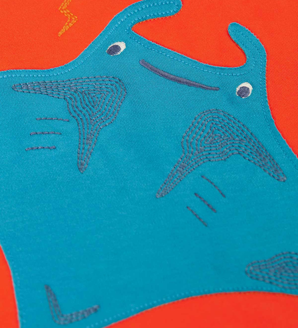 A super close up of the ray on the front of the Frugi orange children's jumper. The blue ray has embroidered details on it.