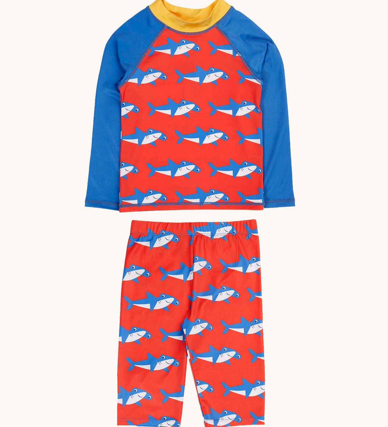 Frugi sun safe swimwear set featuring  a happy hammerheads print , a red background with an all over hammerhead shark print. The set has a long sleeved top with blue sleeves and a yellow collar and a pair of long shorts.