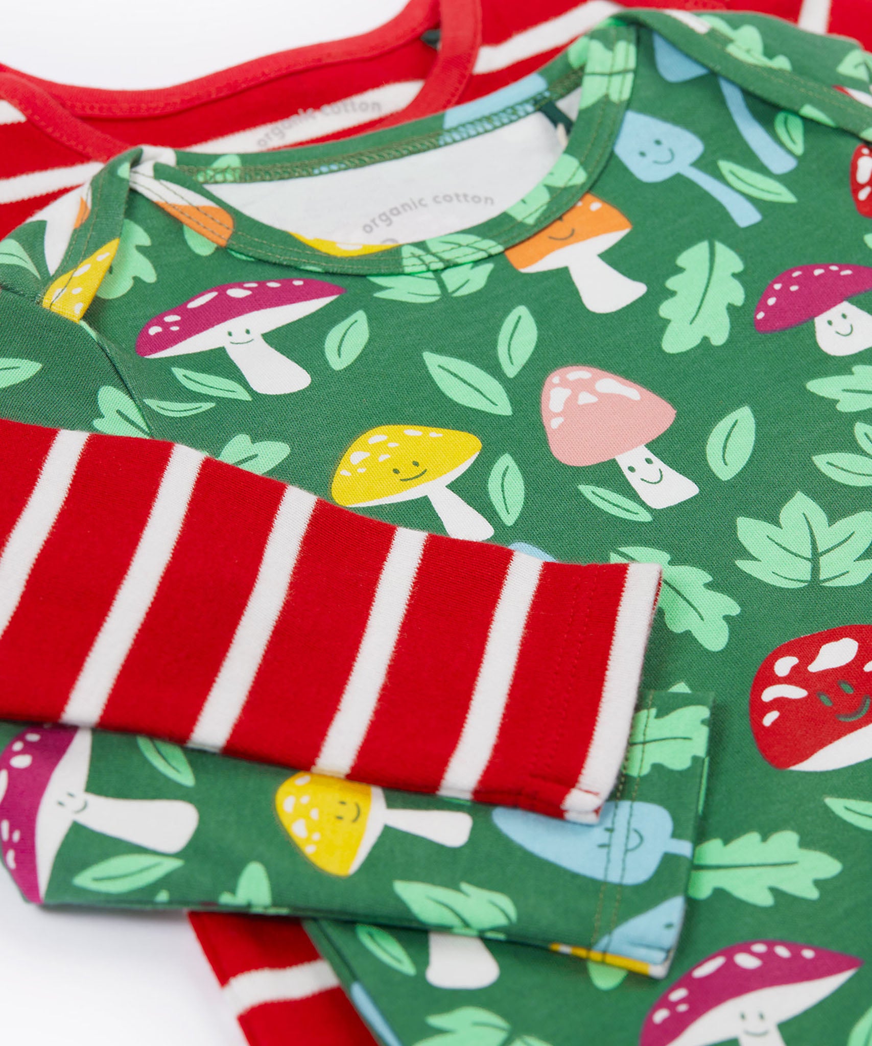 A close up view of the set of two Frugi organic cotton super special long sleeved organic cotton baby vests. The organic cotton vest has one striped vest and one fun guys design vest. 