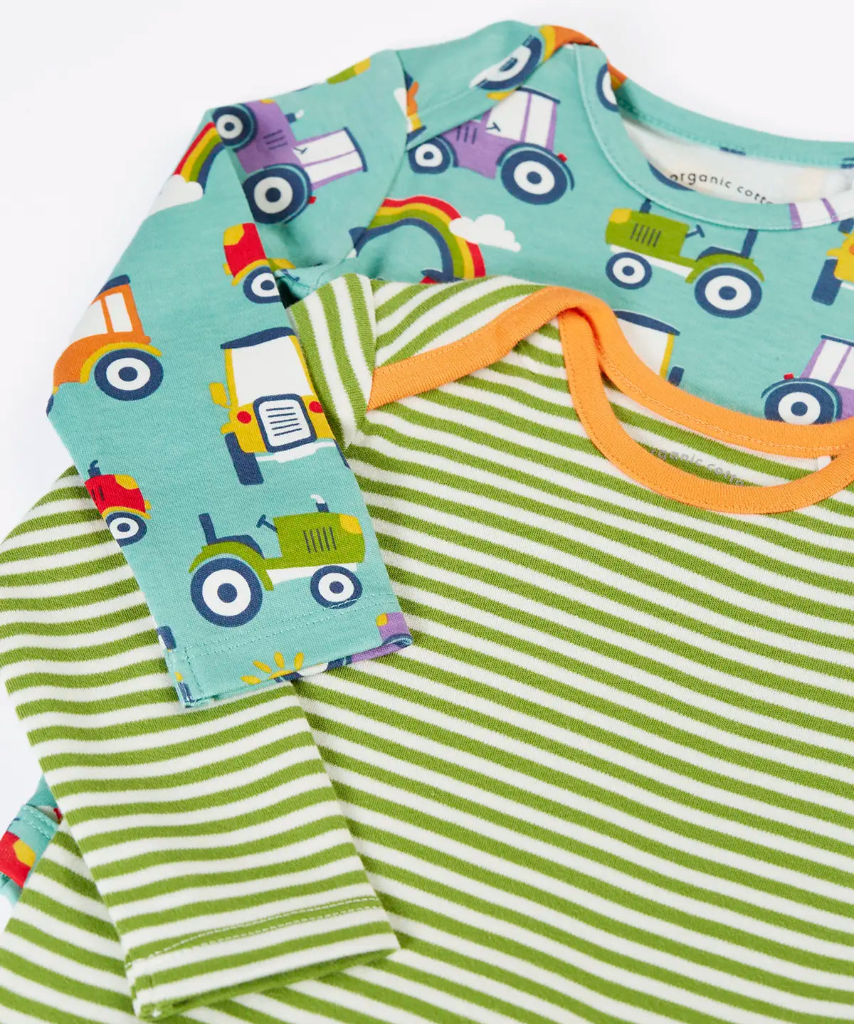Close up of the Frugi super special 2 Pack long sleeves baby body. One has a light green and white , one has an all over terrific tractors print.