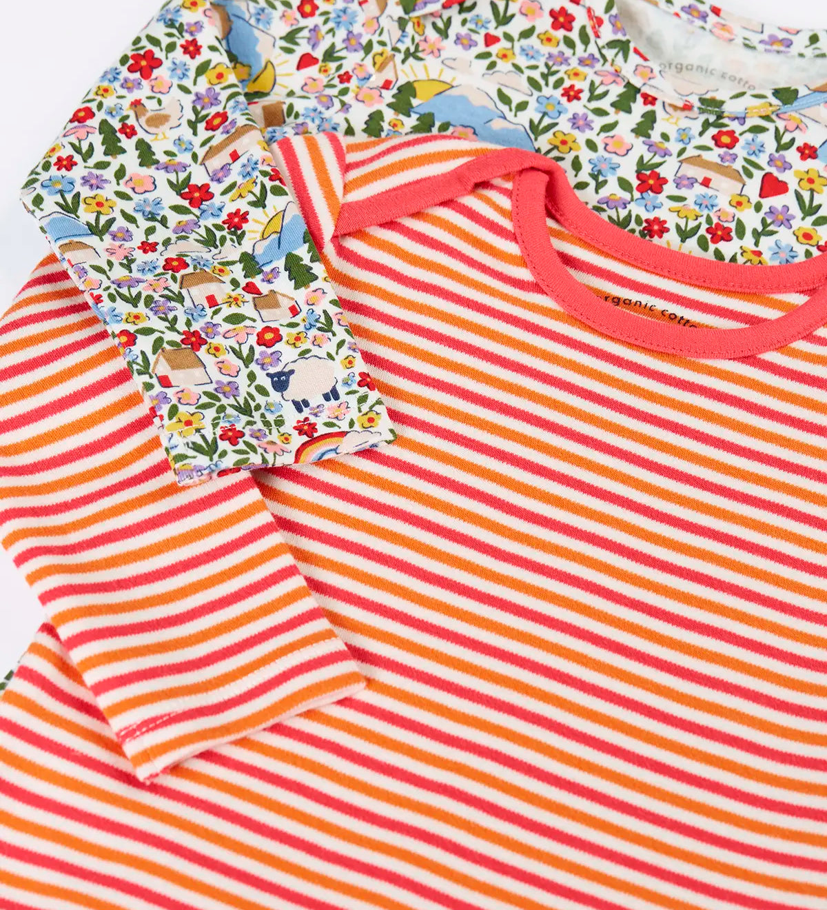 Close up of the front of the Frugi super special 2 Pack long sleeved organic cotton baby body. One has a pink, orange and white stripe, the other had an all over highland fields print.  
