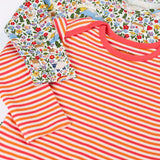 Close up of the front of the Frugi super special 2 Pack long sleeved organic cotton baby body. One has a pink, orange and white stripe, the other had an all over highland fields print.  