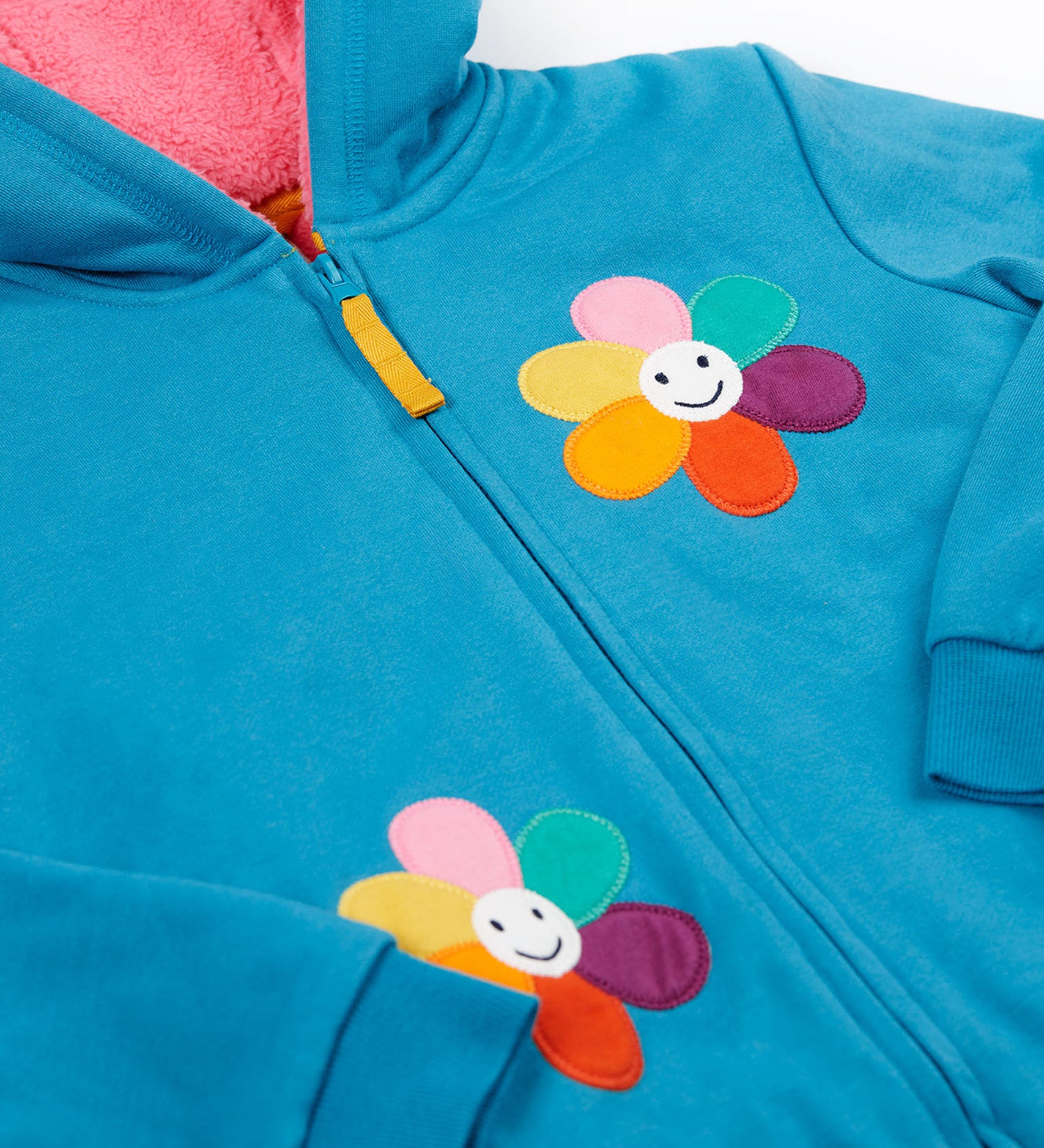 A close up of the Frugi kids ted fleece hoodie in boat blue/flowers showing the full zip detail with yellow toggle and a close up of the playful flower appliqués on bright blue 100% Oeko-Tex cotton 