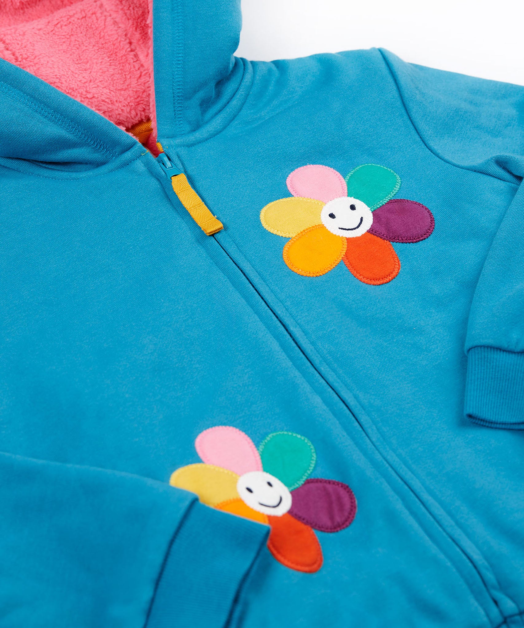 A close up of the Frugi kids ted fleece hoodie in boat blue/flowers showing the full zip detail with yellow toggle and a close up of the playful flower appliqués on bright blue 100% Oeko-Tex cotton 