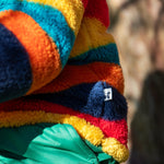 A close up of the small brand tag on the Frugi Autumn stripe ted stripe fleece stitched on the side.