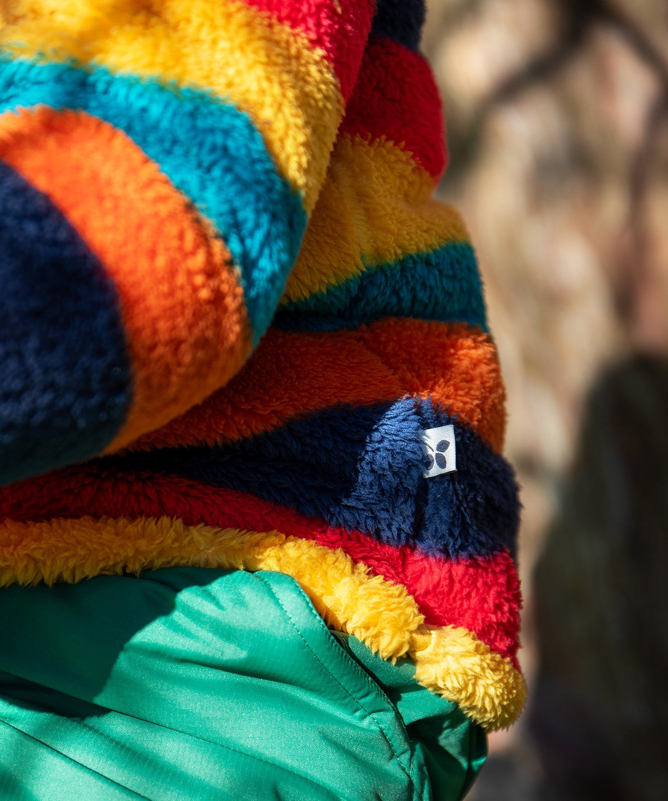 A close up of the small brand tag on the Frugi Autumn stripe ted stripe fleece stitched on the side.