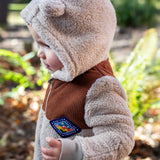 A photo showing the side profile of a child wearing the Frugi cord ted snuggle suit. 