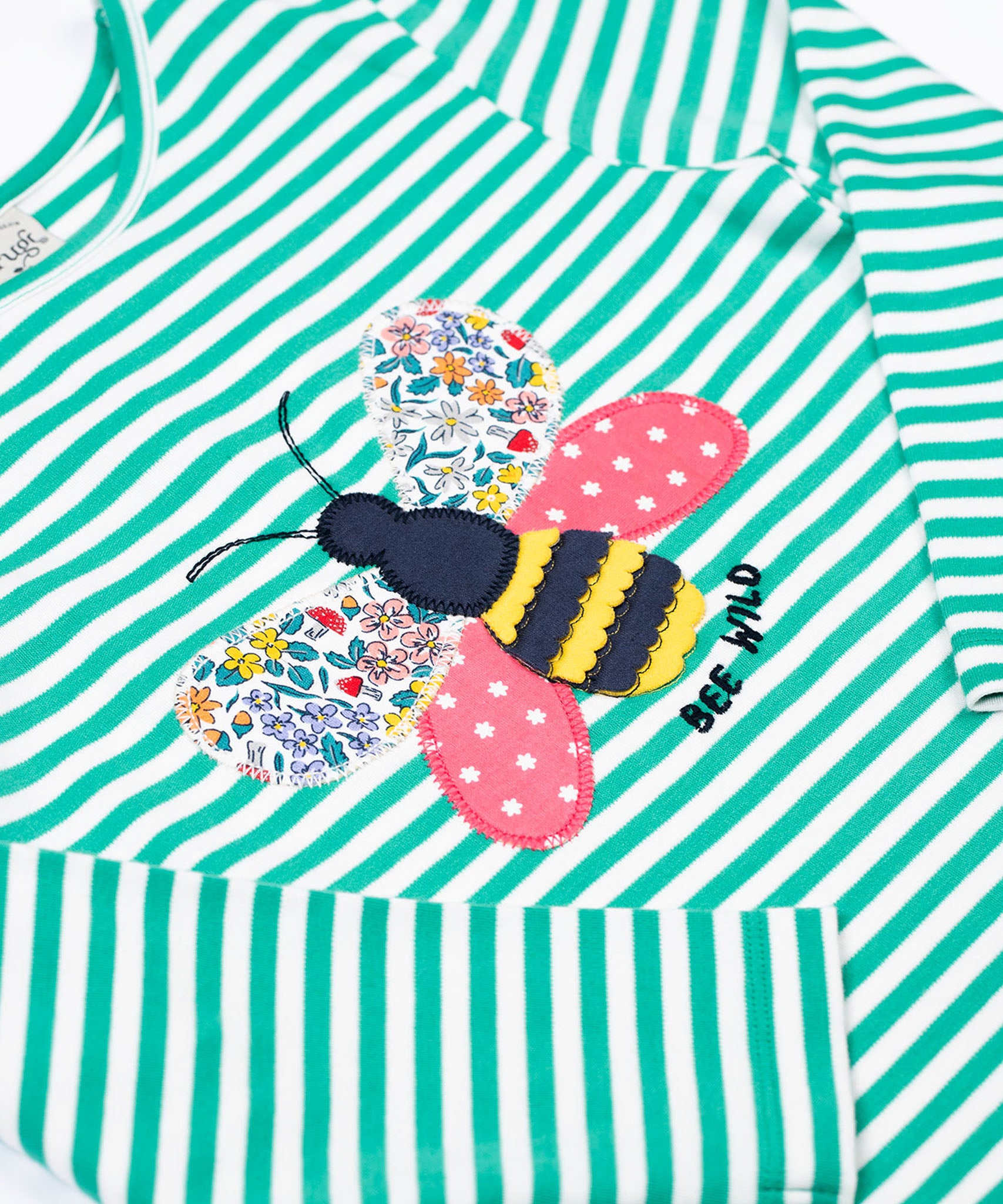 A close up of the bee applique on the front of the Frugi Theresa top with dragon green coloured stripe and bee design.