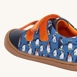A side view of the Frugi Penguin Print Tide Low Top velcro closure leather children's shoes showing the velcro strip closure. 
