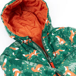 A close up of the Frugi toasty trail reversible jacket showing the playful fox in woodland design with a green zip and hood detail.