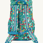 The back of the Frugi kids trail blazing backpack in wild woods showing the shoulder strap detail with blue trim. Features a handy loop for easy carrying and chest buckle for a secure fit