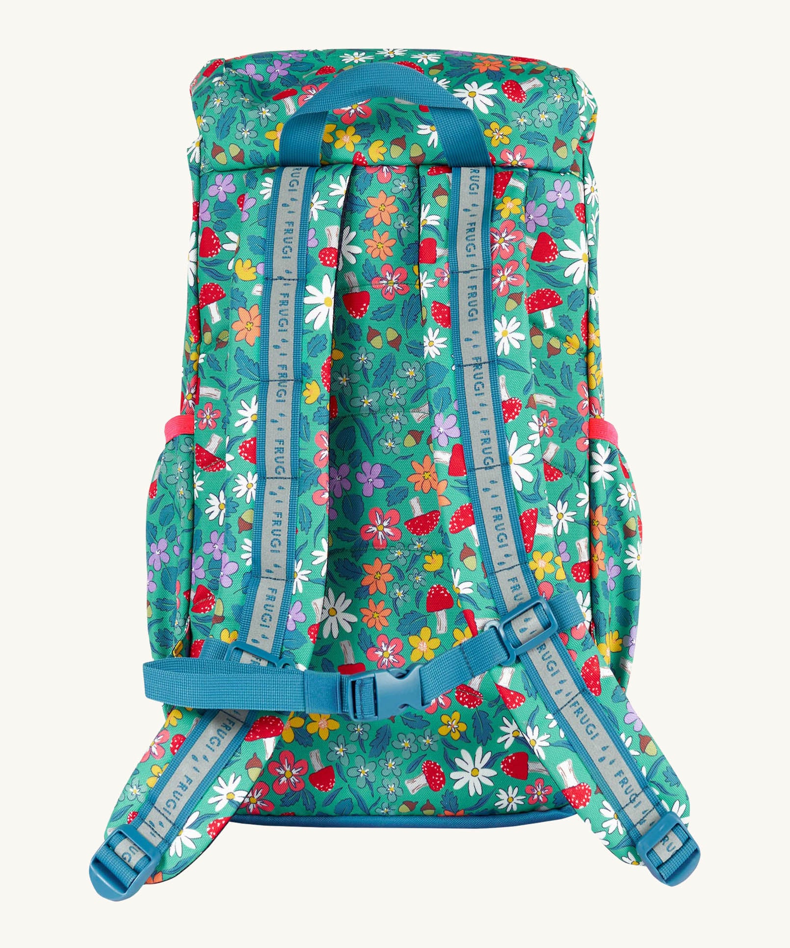 The back of the Frugi kids trail blazing backpack in wild woods showing the shoulder strap detail with blue trim. Features a handy loop for easy carrying and chest buckle for a secure fit
