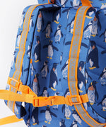 A close up of the Frugi kids trail blazing backpack in penguin waddle. Showing the shoulder strap detail and orange chest buckle connecting the shoulder straps