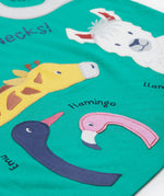 A close up of the Frugi kids long neck pals t-shirt. Showing the different long necked animals appliqué including a giraffe and emu, flamingo and llama with animal names on green organic cotton fabric