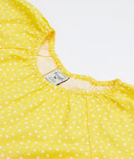 A close up of Frugi Dorothy Twirly Dress in its Rainbow Hotchpotch print, featuring a spotty yellow design.