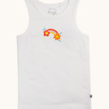 The white vest with rainbow flower graphic from the Frugi varlie bloom vest 2 pack multipack. The sleeveless children's vest has a graphic in the middle of the chest featuring an orange pink and yellow rainbow with  a flower each end of the rainbow on a crisp white background.