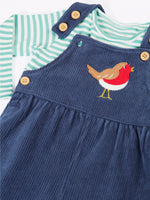 Close up of the Frugi veryan organic cotton navy cord dungaree with robin applique with long sleeve green and white striped bodysuit baby outfit showing the dungaree strap open.