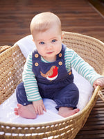 Baby sitting up wearing the Frugi veryan organic cotton navy cord dungaree baby outfit with long sleeve green and white striped bodysuit.