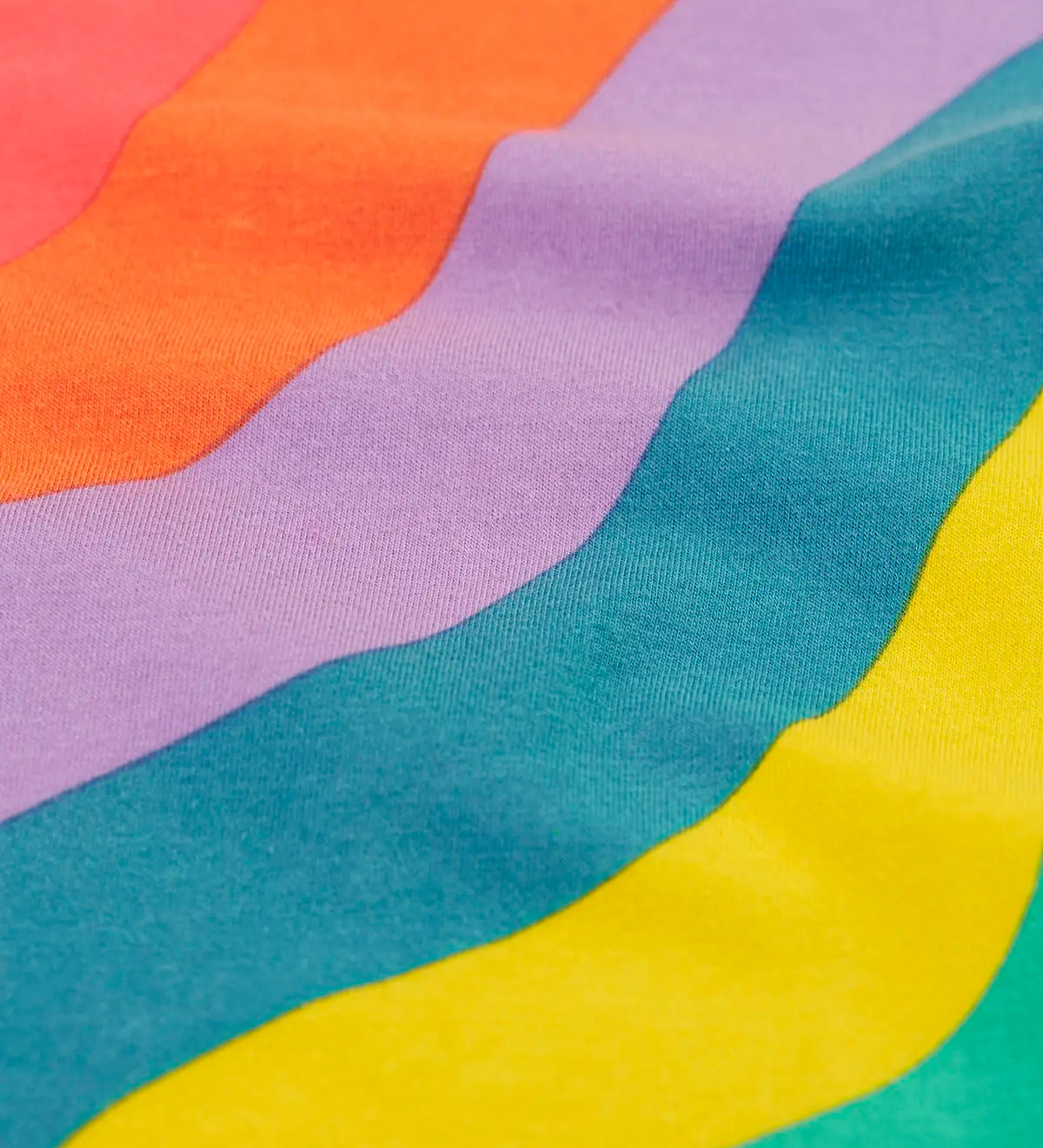 Close up of the Frugi ric rac rainbow organic cotton material on the wide leg children's trousers. 