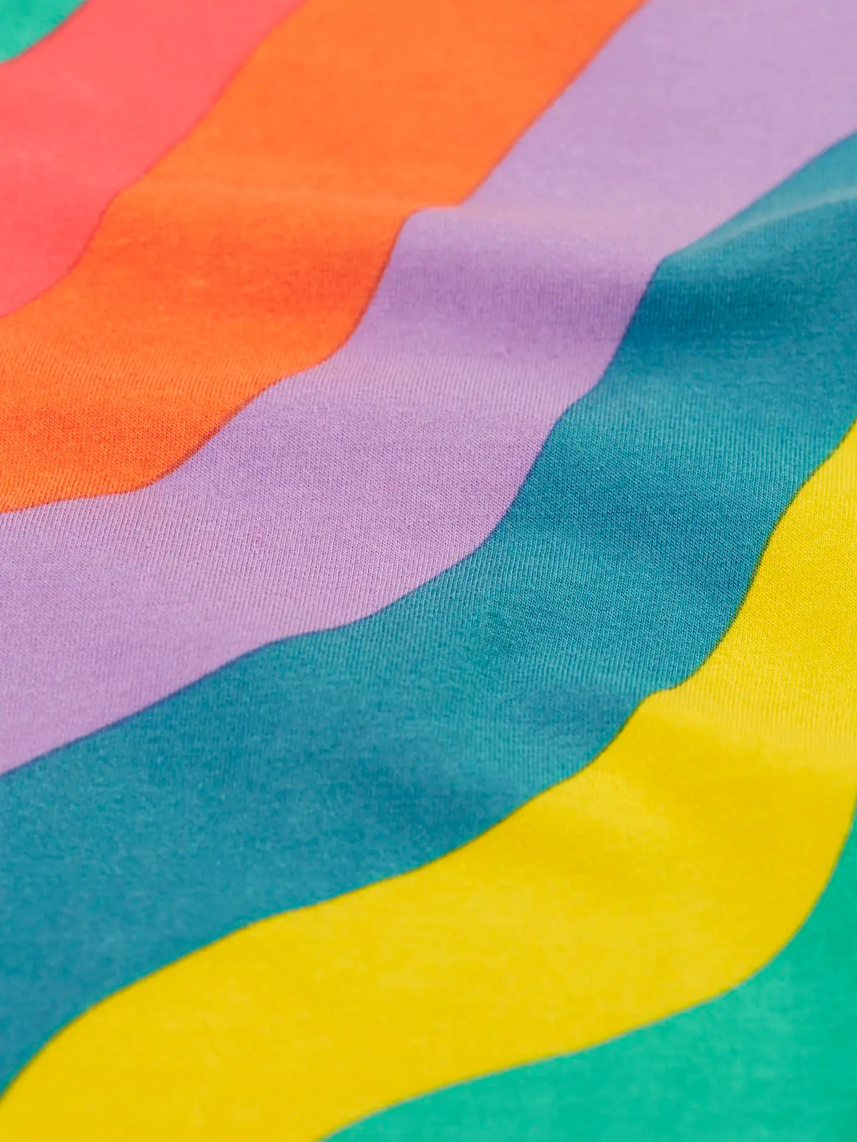Close up of the Frugi ric rac rainbow organic cotton material on the wide leg children's trousers. 