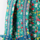 A close up of the Frugi kids trail blazing backpack in wild woods. Showing the shoulder strap detail and blue chest buckle connecting the shoulder straps