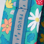 A close up of the shoulder strap on the Frugi kids trail blazing backpack in wild woods. Showing the reflective strip running down the strap