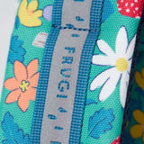 A close up of the shoulder strap on the Frugi kids trail blazing backpack in wild woods. Showing the reflective strip running down the strap
