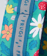 A close up of the shoulder strap on the Frugi kids trail blazing backpack in wild woods. Showing the reflective strip running down the strap