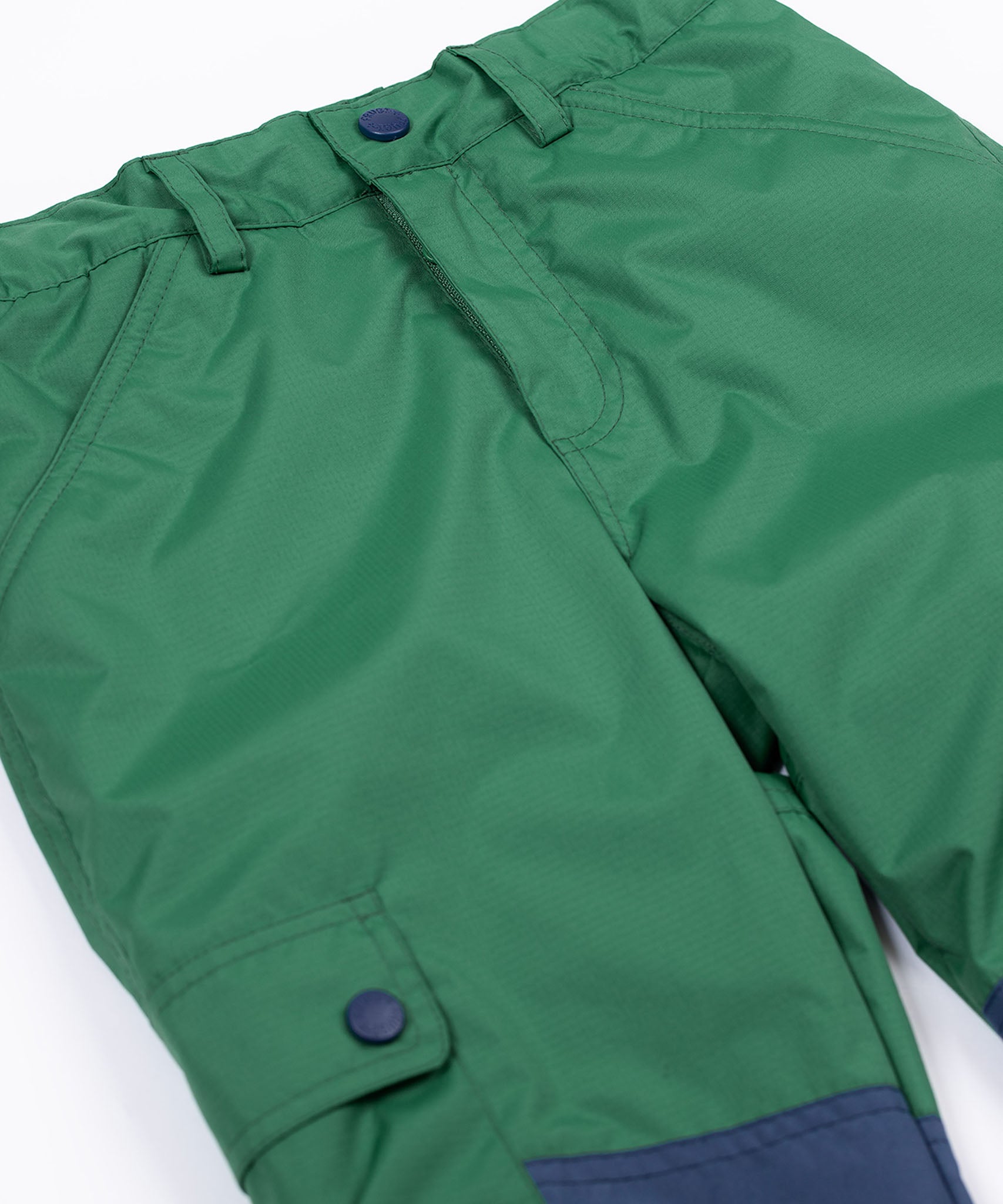 A close up of the Frugi Wilderness green trousers with navy blue coloured knee patches.