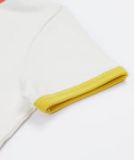 A close up of Frugi Xavier Circus T-Shirt's sleeve, a Soft White t-shirt with a yellow hem detail.