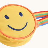 A close up of the front of the Frugi yellow happy smiley face children's rainbow coloured belt bag. 